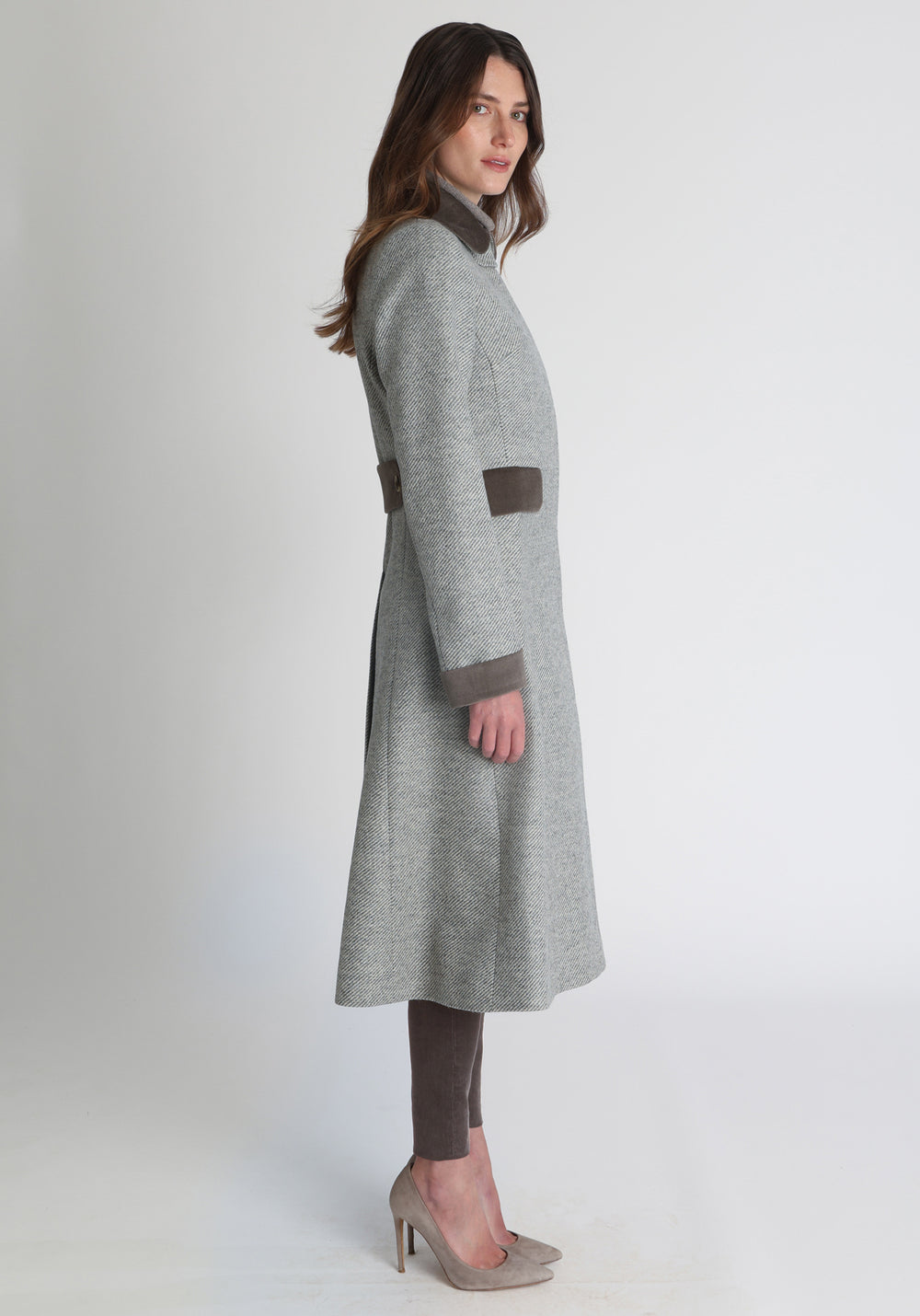 Model wearing the Contrast coat in slate blue and cream twill lambswool with cotton velvet detailing on the collar, cuffs, back belt, and pocket flaps, a longline occasion wear style with a timeless silhouette.