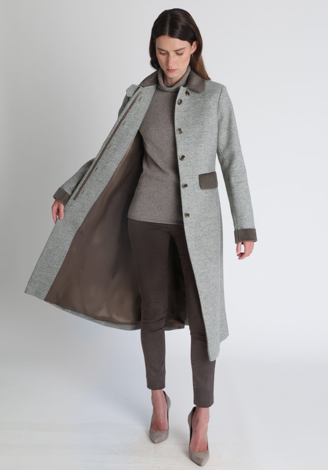 Model wearing the Contrast coat in slate blue and cream twill lambswool with cotton velvet detailing on the collar, cuffs, back belt, and pocket flaps, a longline occasion wear style with a timeless silhouette.