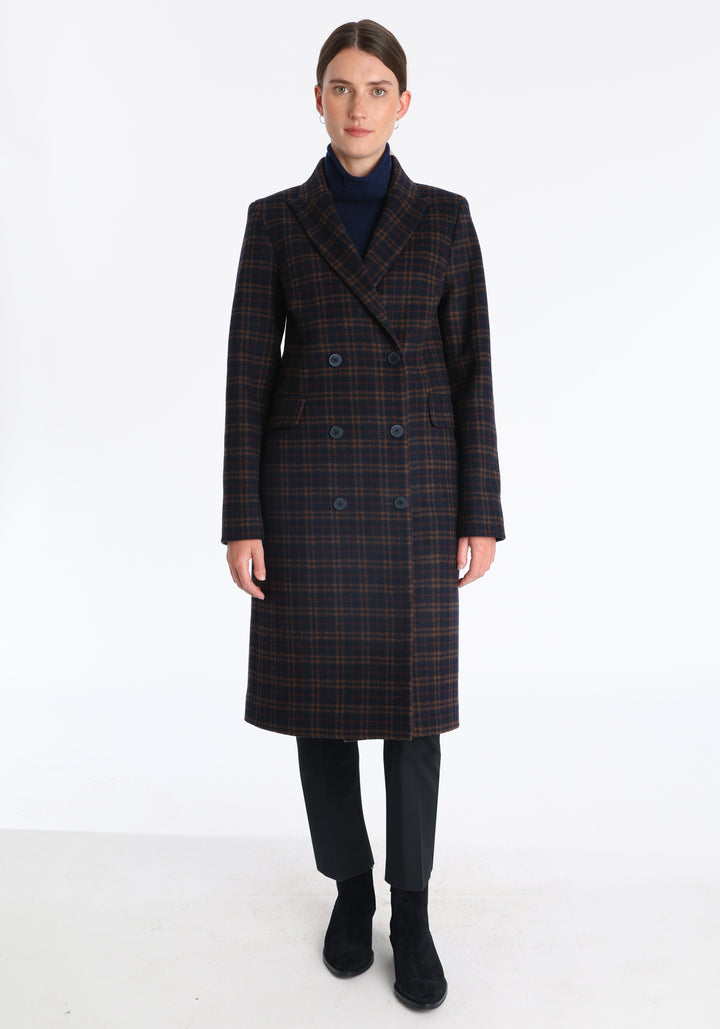 Model wearing the Cully coat in navy and rust check merino wool, a knee-length, double-breasted style with pointed lapels and a structured, straight-cut silhouette designed to flatter.