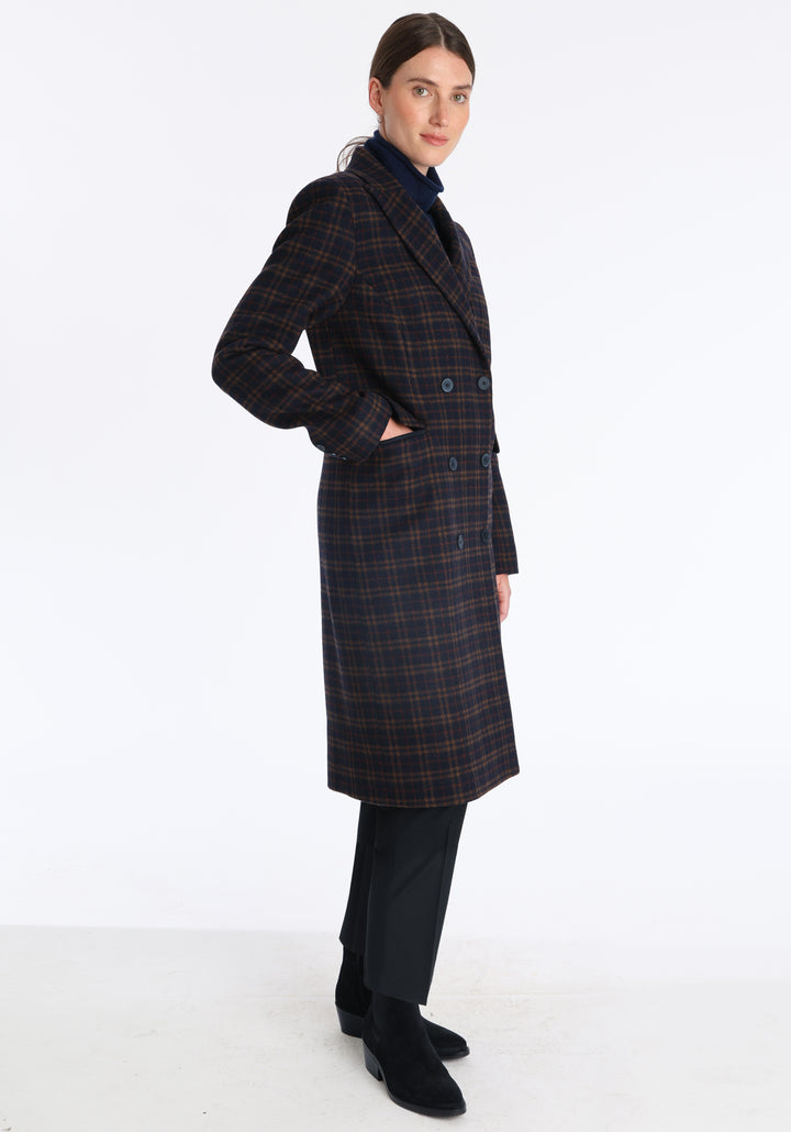 Model wearing the Cully coat in navy and rust check merino wool, a knee-length, double-breasted style with pointed lapels and a structured, straight-cut silhouette designed to flatter.