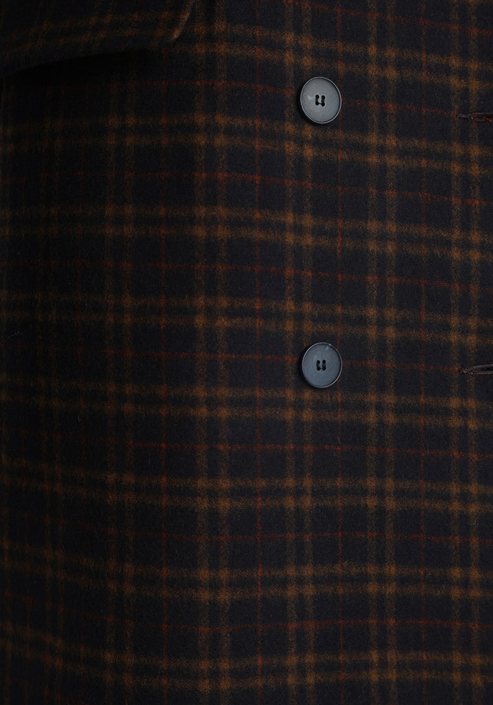 Model wearing the Cully coat in navy and rust check merino wool, a knee-length, double-breasted style with pointed lapels and a structured, straight-cut silhouette designed to flatter.