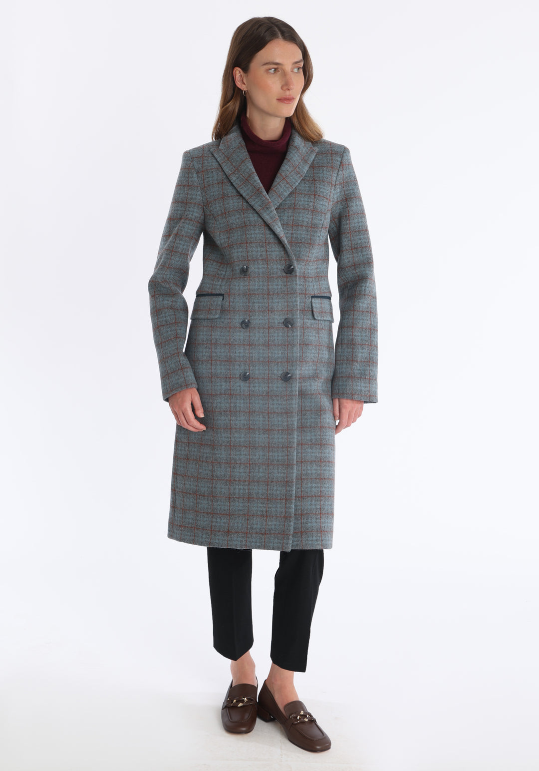 Model wearing the Cully coat in silver and rust check merino wool, a knee-length, double-breasted style with pointed lapels and a structured, straight-cut silhouette designed to flatter.