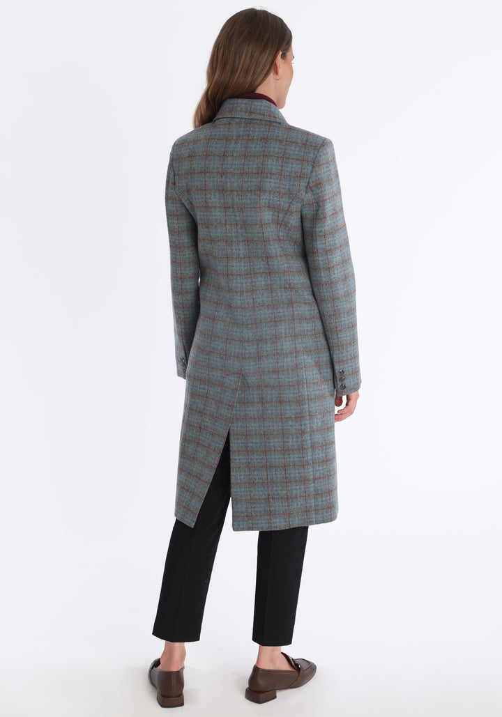 Model wearing the Cully coat in silver and rust check merino wool, a knee-length, double-breasted style with pointed lapels and a structured, straight-cut silhouette designed to flatter.
