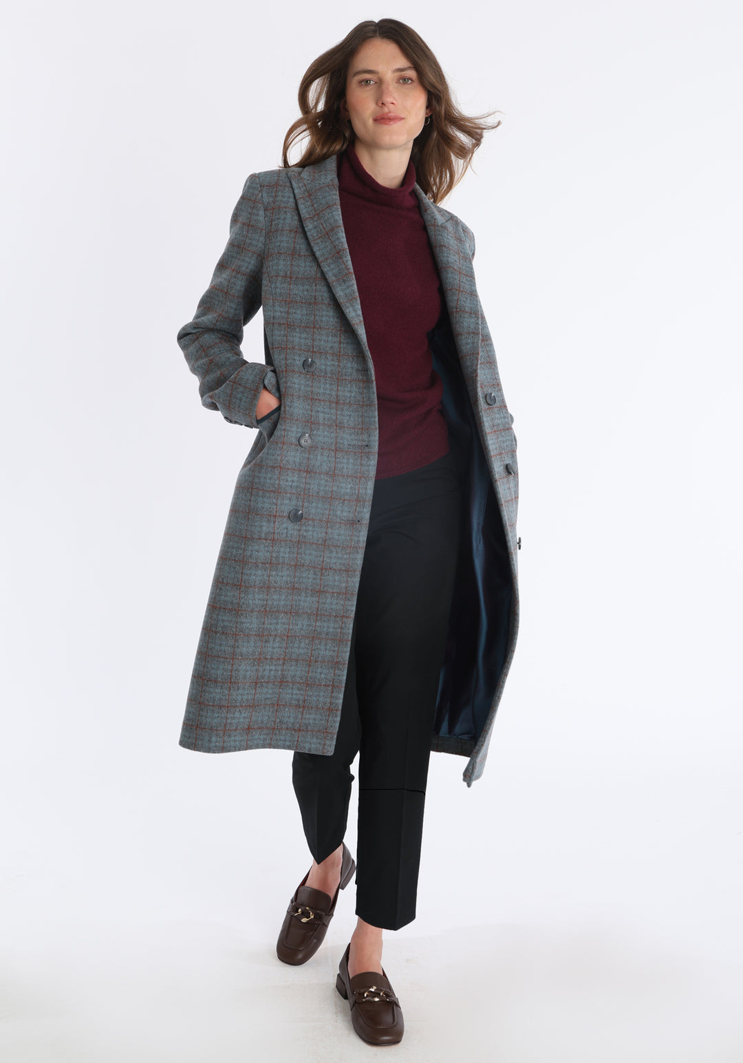 Model wearing the Cully coat in silver and rust check merino wool, a knee-length, double-breasted style with pointed lapels and a structured, straight-cut silhouette designed to flatter.