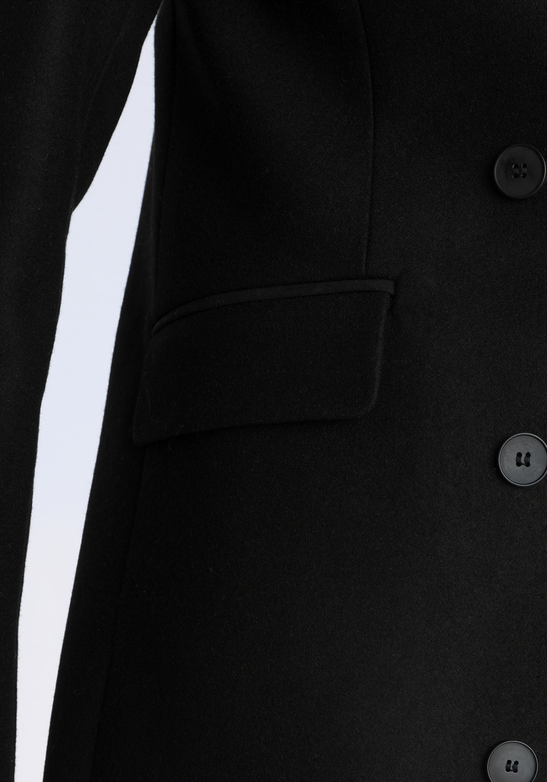 Model wearing the Cully coat in black cashmere blend, a knee-length, double-breasted style with pointed lapels and a structured, straight-cut silhouette designed to flatter.