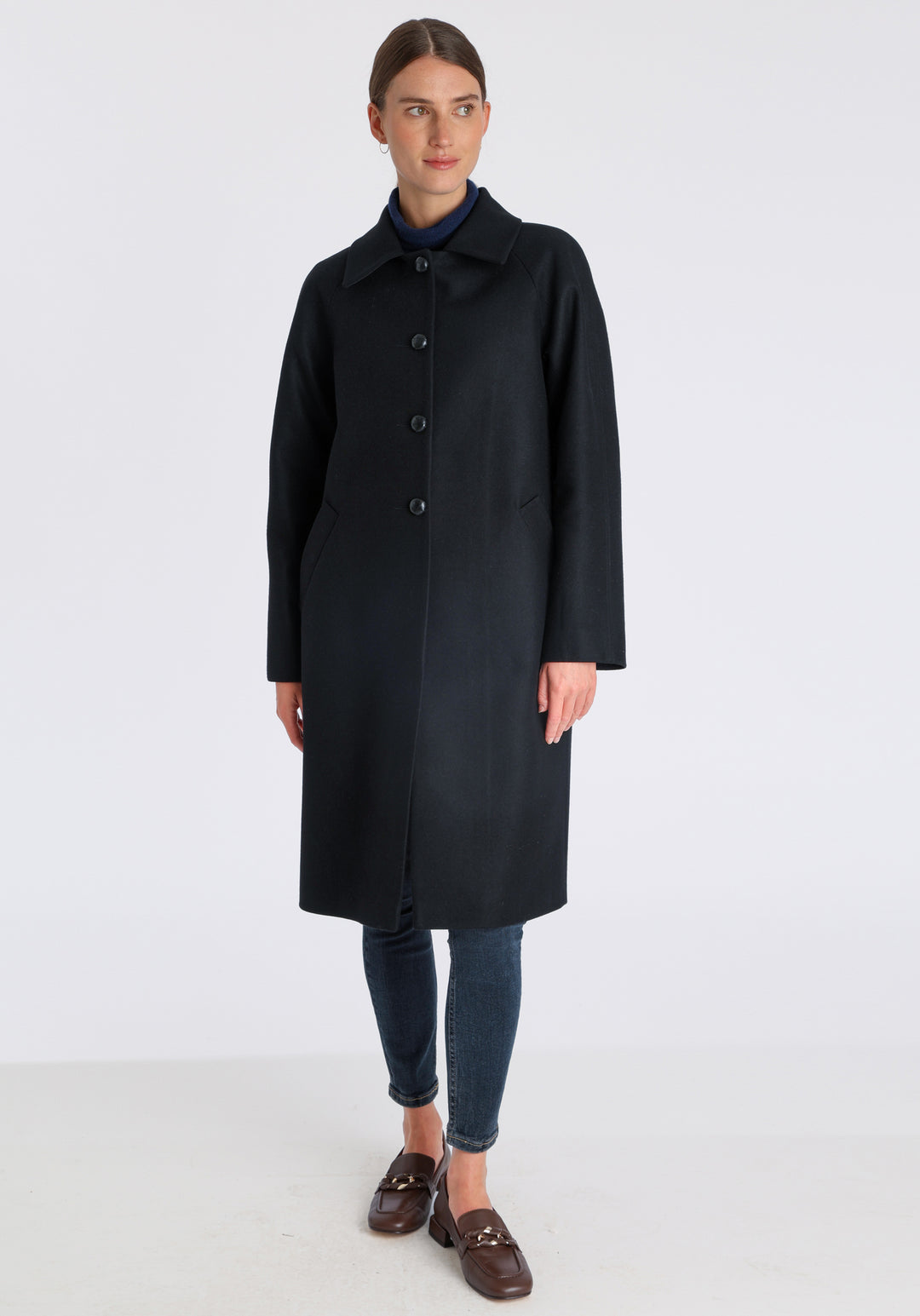 Model wearing the Dari coat in black cashmere blend, a relaxed cocoon-shaped style with raglan sleeves, finished with suede trim.