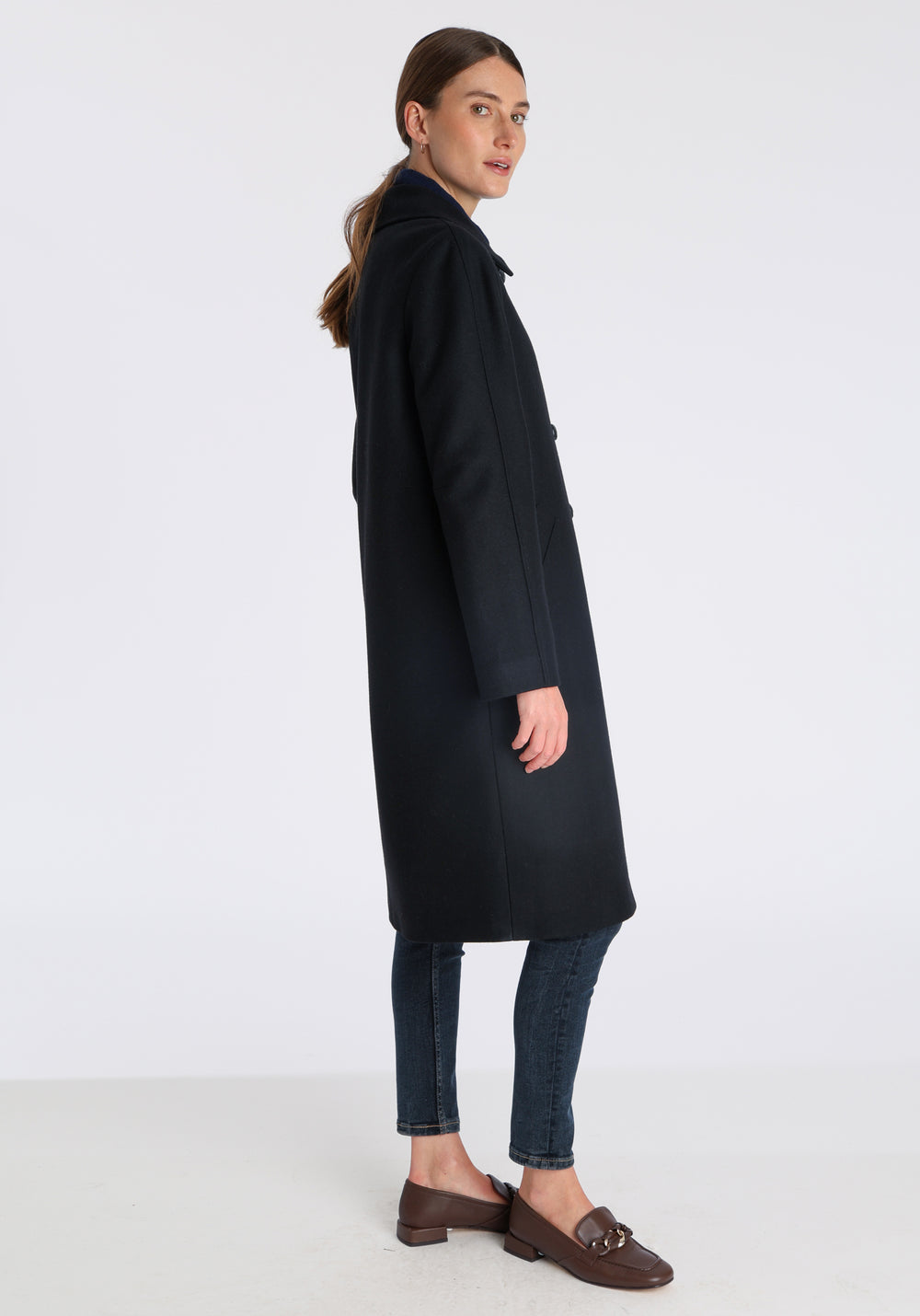 Model wearing the Dari coat in black cashmere blend, a relaxed cocoon-shaped style with raglan sleeves, finished with suede trim.