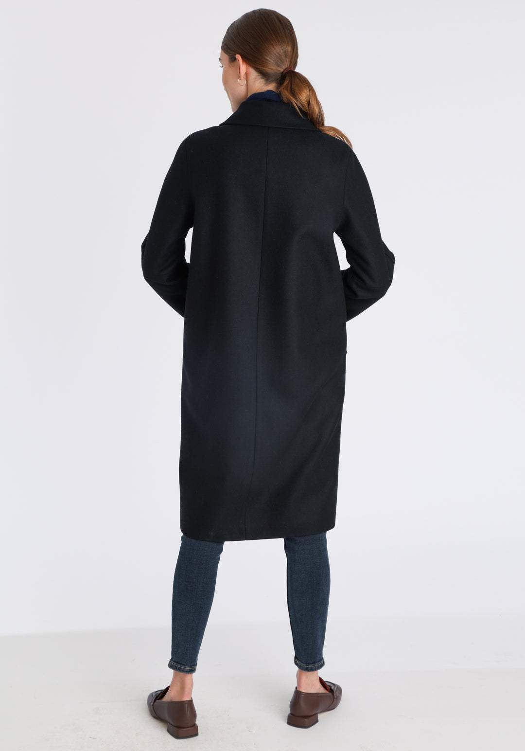 Model wearing the Dari coat in black cashmere blend, a relaxed cocoon-shaped style with raglan sleeves, finished with suede trim.