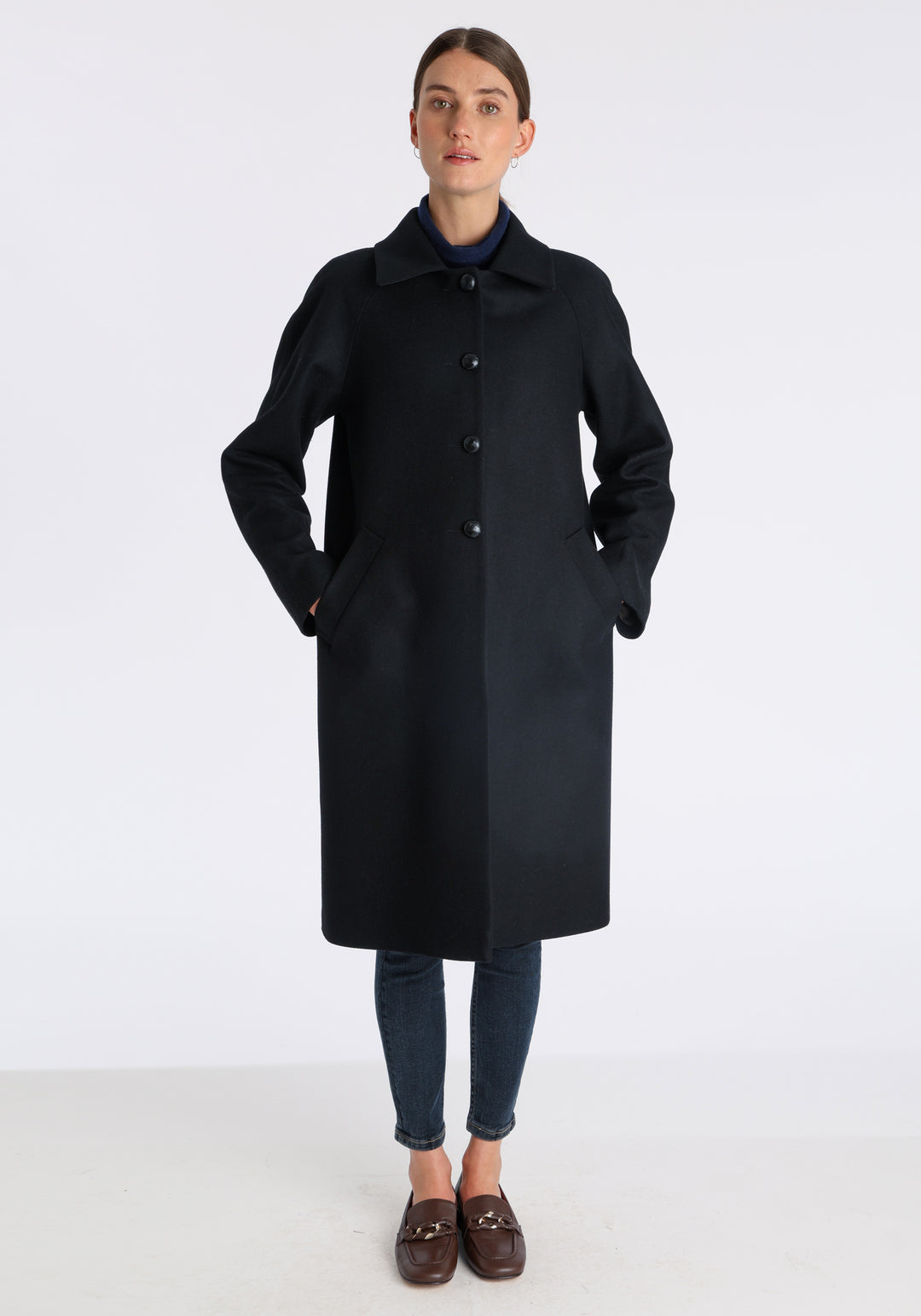Model wearing the Dari coat in black cashmere blend, a relaxed cocoon-shaped style with raglan sleeves, finished with suede trim.
