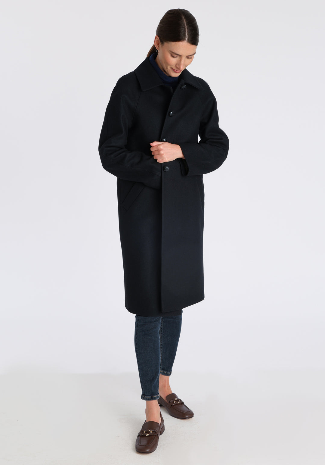 Model wearing the Dari coat in black cashmere blend, a relaxed cocoon-shaped style with raglan sleeves, finished with suede trim.