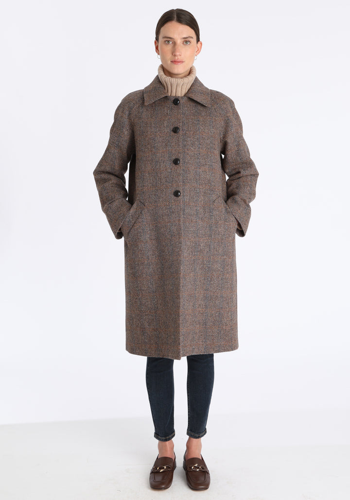 Model wearing the Dari coat in clay check Harris Tweed, a relaxed cocoon-shaped style with raglan sleeves, finished with chocolate suede under the collar.
