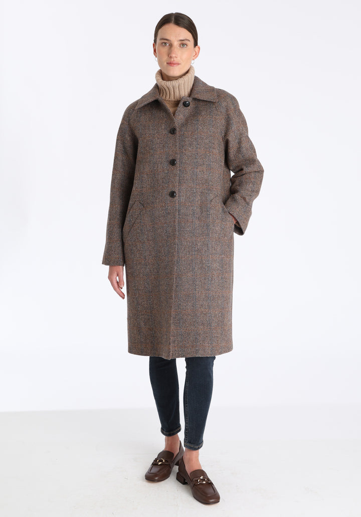 Model wearing the Dari coat in clay check Harris Tweed, a relaxed cocoon-shaped style with raglan sleeves, finished with chocolate suede under the collar.