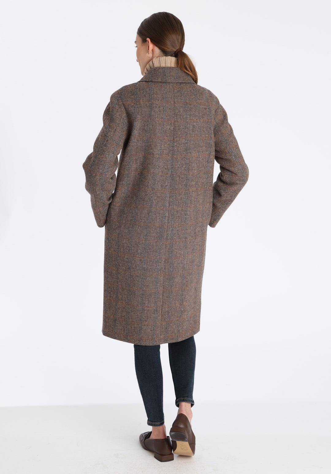 Model wearing the Dari coat in clay check Harris Tweed, a relaxed cocoon-shaped style with raglan sleeves, finished with chocolate suede under the collar.
