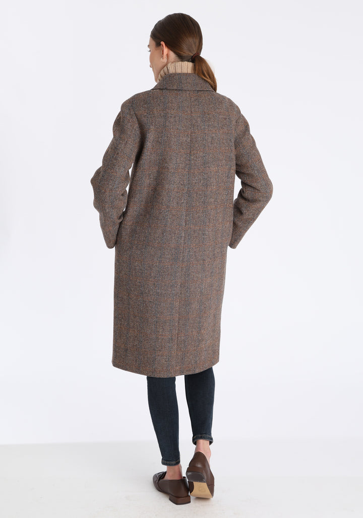 Model wearing the Dari coat in clay check Harris Tweed, a relaxed cocoon-shaped style with raglan sleeves, finished with chocolate suede under the collar.