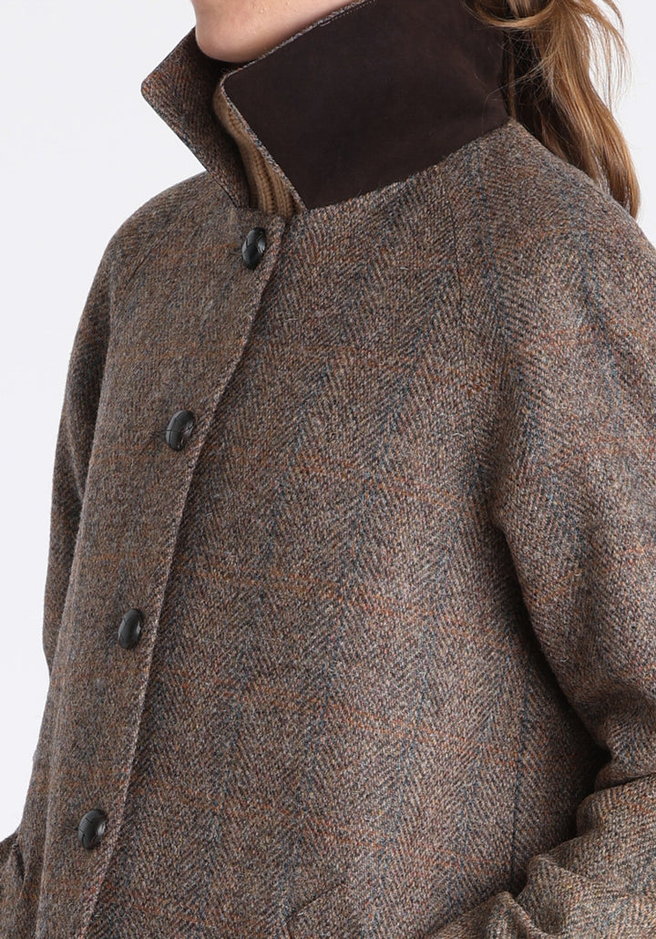Model wearing the Dari coat in clay check Harris Tweed, a relaxed cocoon-shaped style with raglan sleeves, finished with chocolate suede under the collar.