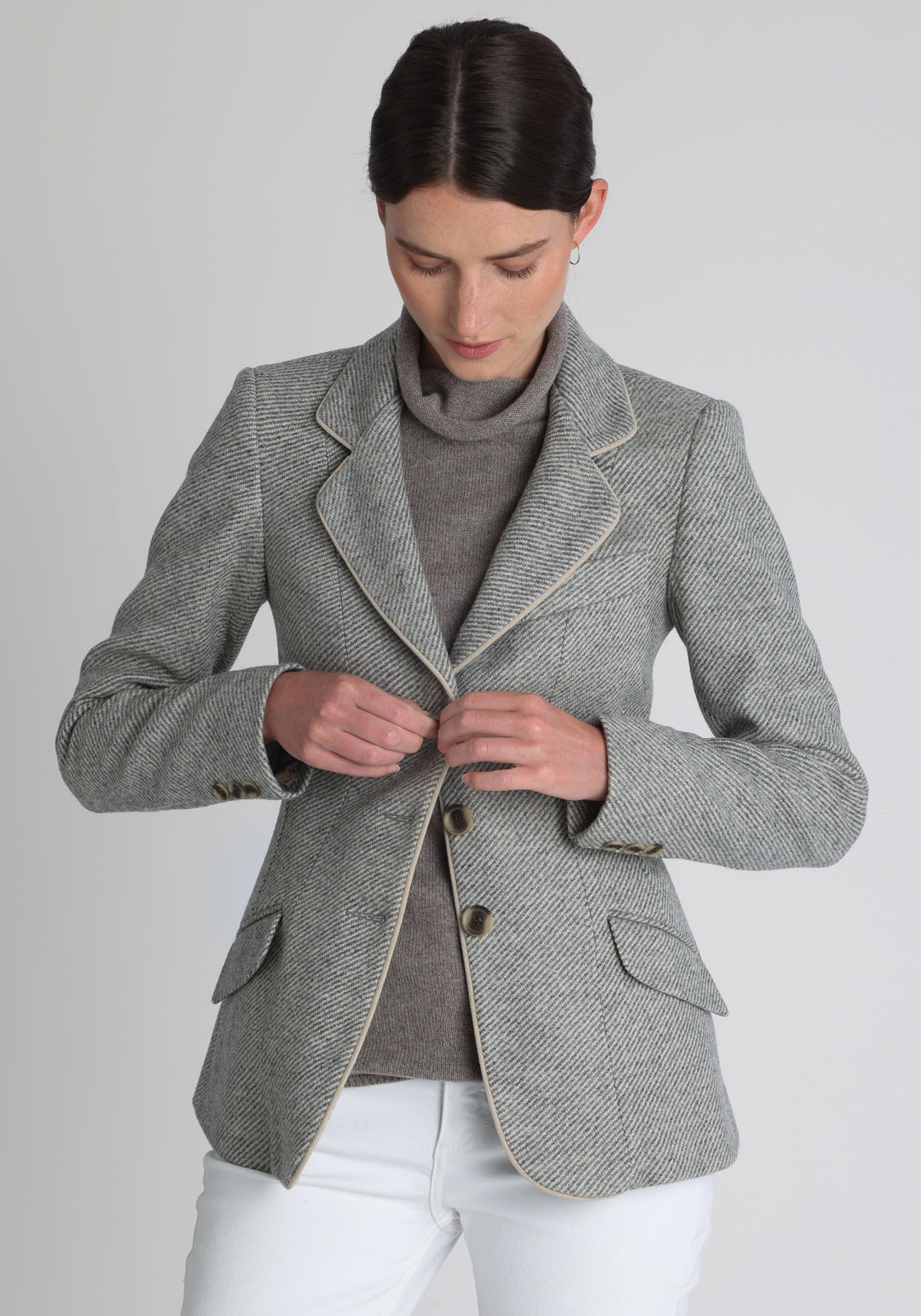 Model wearing the Hacking jacket slate blue and cream twill lambswool, a slim fit style with notched lapels, angled hip pockets, and a single back vent, inspired by traditional equestrian tailoring.