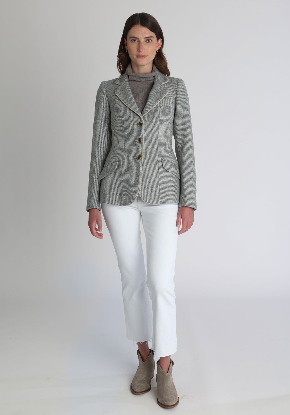 Model wearing the Hacking jacket slate blue and cream twill lambswool, a slim fit style with notched lapels, angled hip pockets, and a single back vent, inspired by traditional equestrian tailoring.