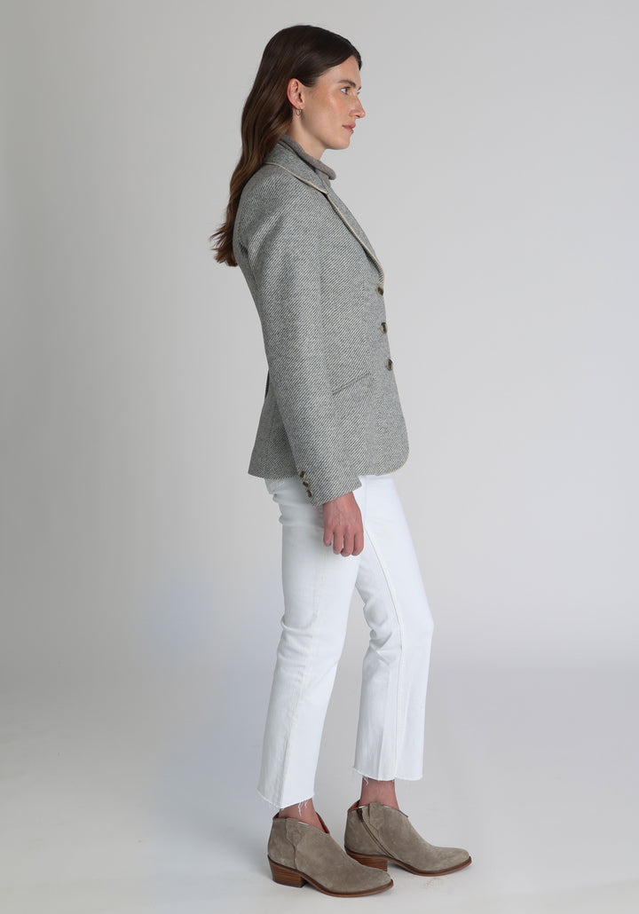 Model wearing the Hacking jacket slate blue and cream twill lambswool, a slim fit style with notched lapels, angled hip pockets, and a single back vent, inspired by traditional equestrian tailoring.