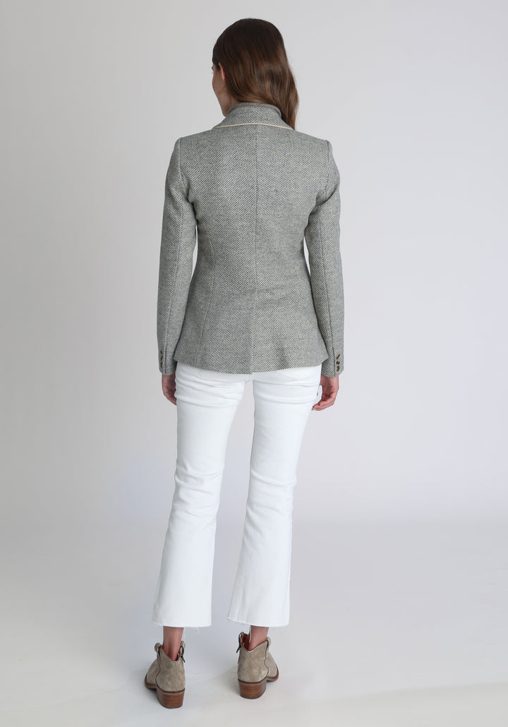 Model wearing the Hacking jacket slate blue and cream twill lambswool, a slim fit style with notched lapels, angled hip pockets, and a single back vent, inspired by traditional equestrian tailoring.