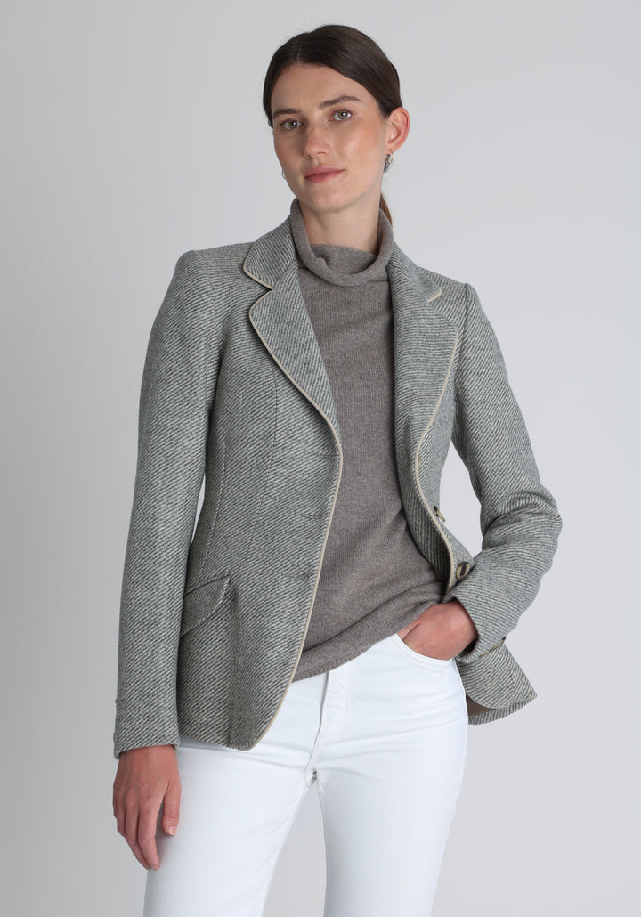 Model wearing the Hacking jacket slate blue and cream twill lambswool, a slim fit style with notched lapels, angled hip pockets, and a single back vent, inspired by traditional equestrian tailoring.