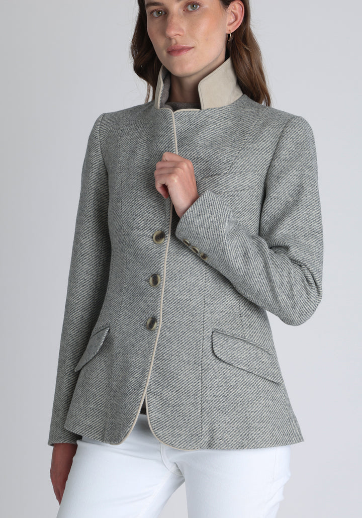 Model wearing the Hacking jacket slate blue and cream twill lambswool, a slim fit style with notched lapels, angled hip pockets, and a single back vent, inspired by traditional equestrian tailoring.