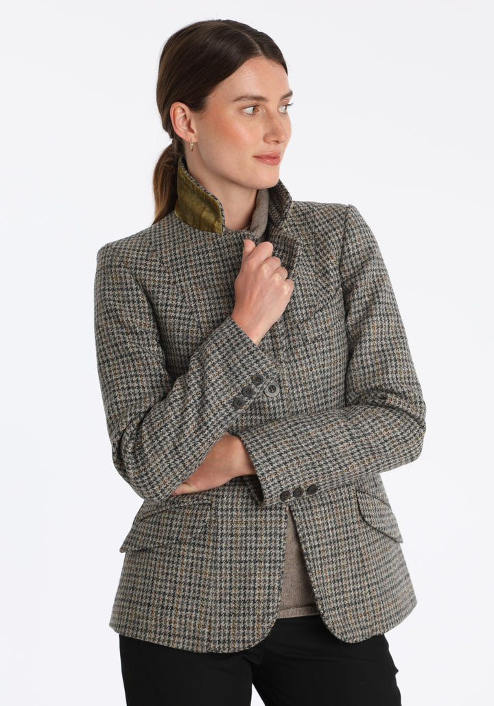 Model wearing the Hacking jacket in a stone grey and ochre dogtooth wool, a slim fit style with notched lapels, angled hip pockets, and a single back vent, inspired by traditional equestrian tailoring.