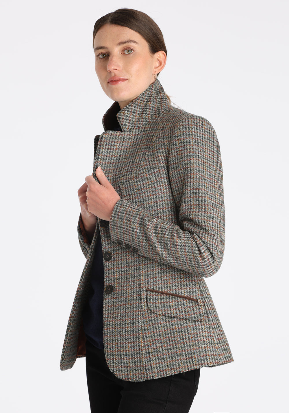 Model wearing the Hacking jacket in an autumnal cinder check wool, a slim fit style with notched lapels, angled hip pockets, and a single back vent, inspired by traditional equestrian tailoring.