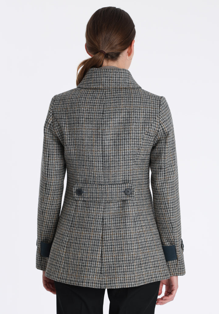Model wearing the Hendre jacket in grey and ochre dogtooth check, a structured style with a high collar, reversible suede cuff bands, and a back belt for versatile styling.