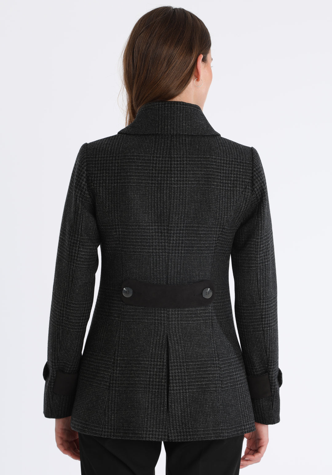 Model wearing the Hendre jacket in black and grey Prince of Wales check, a structured style with a high collar, reversible suede cuff bands, and a back belt for versatile styling.