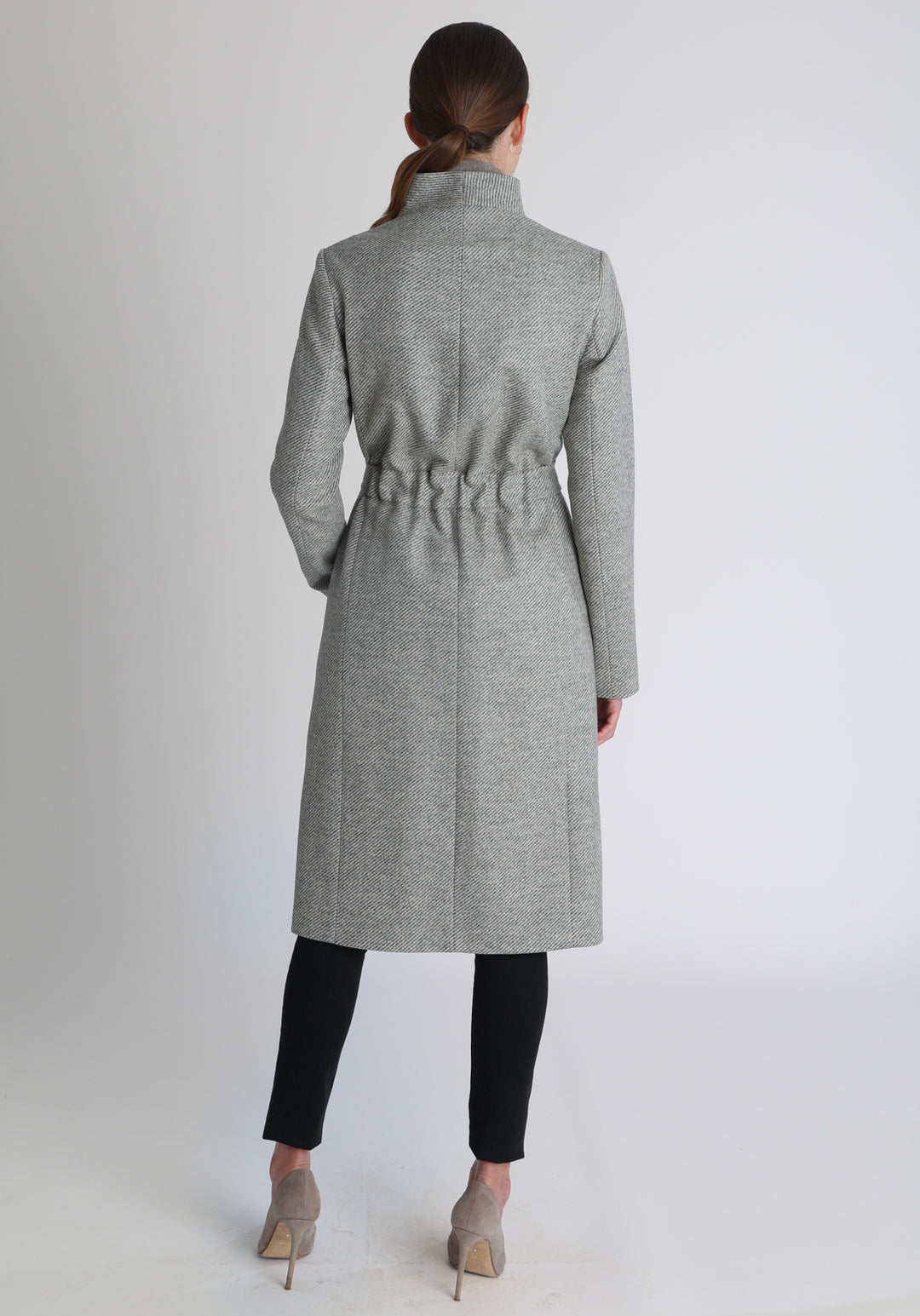 Model wearing the Hillsy coat in slate blue and cream lambswool twill, a wrap-style design with a standing collar and tie belt, offering a softly tailored, elegant silhouette. 