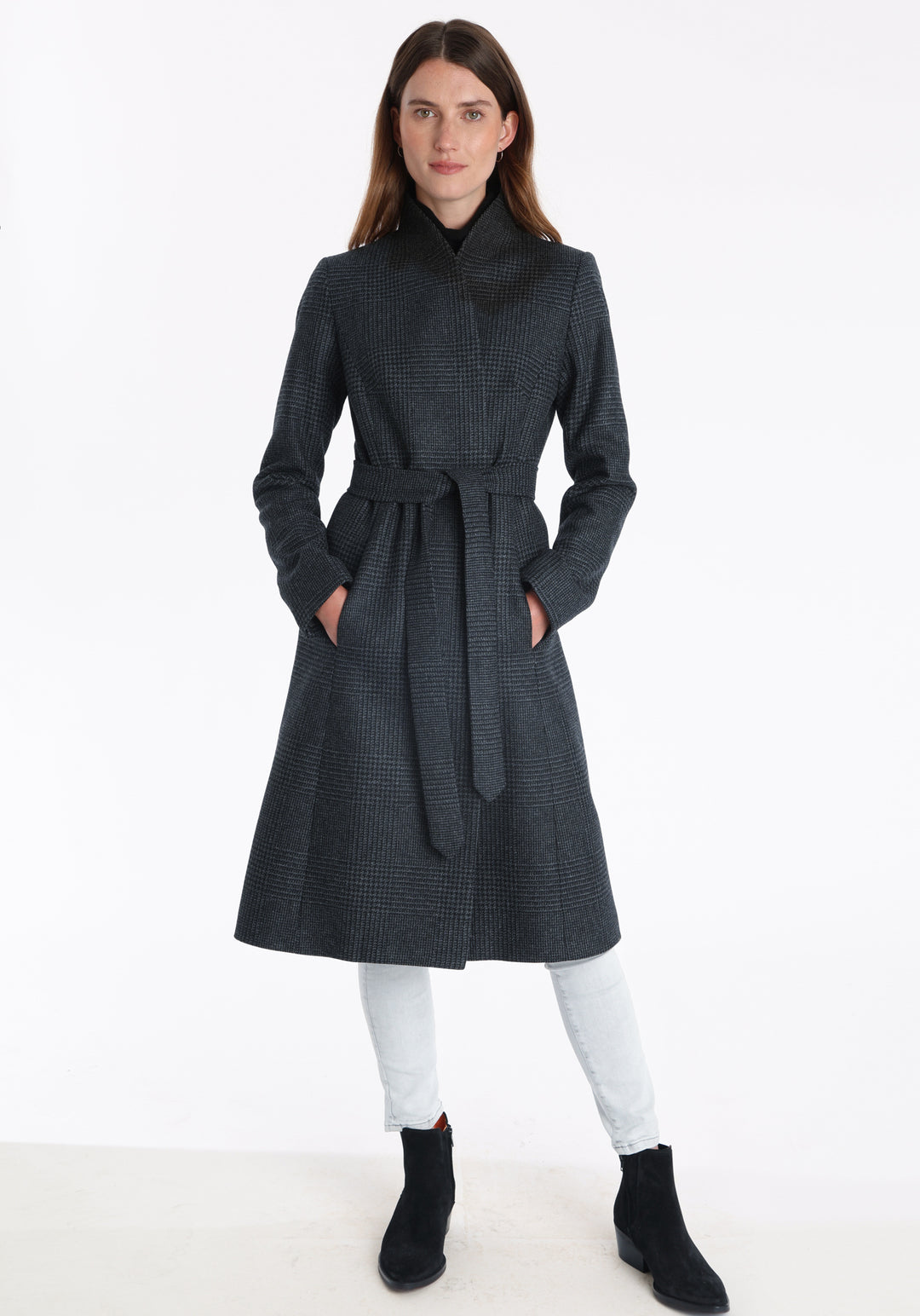 Model wearing the Hillsy coat in a black and charcoal grey Prince of Wales check, a wrap-style design with a standing collar, and tie belt, offering a softly tailored, elegant silhouette.