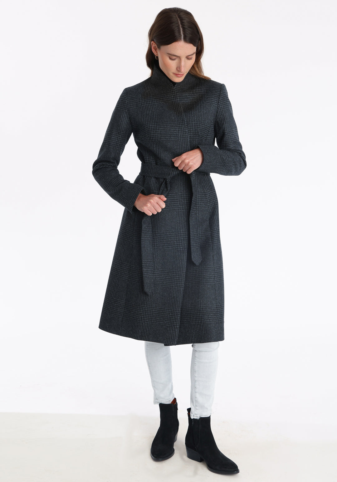 Model wearing the Hillsy coat in a black and charcoal grey Prince of Wales check, a wrap-style design with a standing collar, and tie belt, offering a softly tailored, elegant silhouette.
