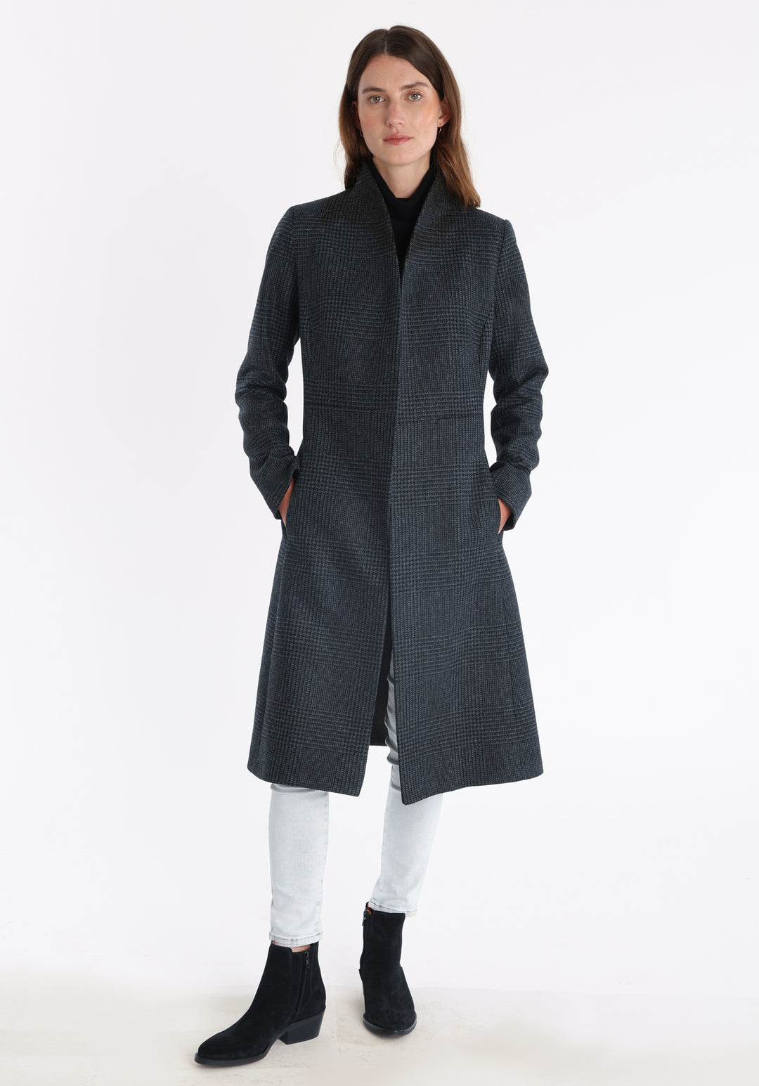 Model wearing the Hillsy coat in a black and charcoal grey Prince of Wales check, a wrap-style design with a standing collar, and tie belt, offering a softly tailored, elegant silhouette.