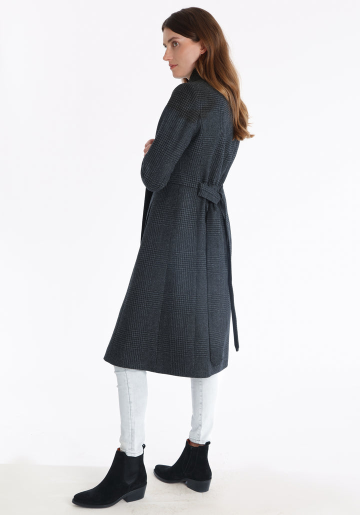 Model wearing the Hillsy coat in a black and charcoal grey Prince of Wales check, a wrap-style design with a standing collar, and tie belt, offering a softly tailored, elegant silhouette.