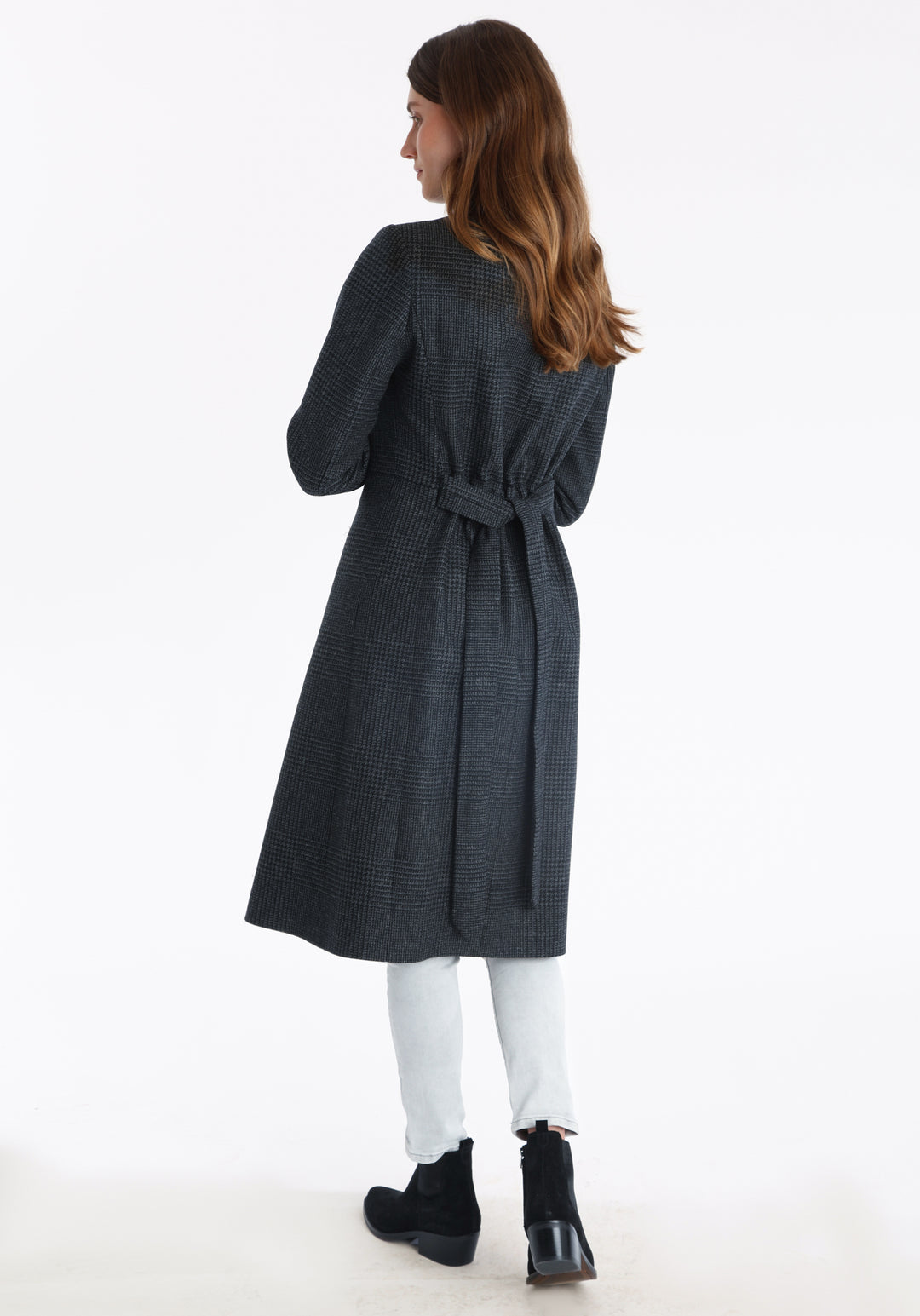 Model wearing the Hillsy coat in a black and charcoal grey Prince of Wales check, a wrap-style design with a standing collar, and tie belt, offering a softly tailored, elegant silhouette.