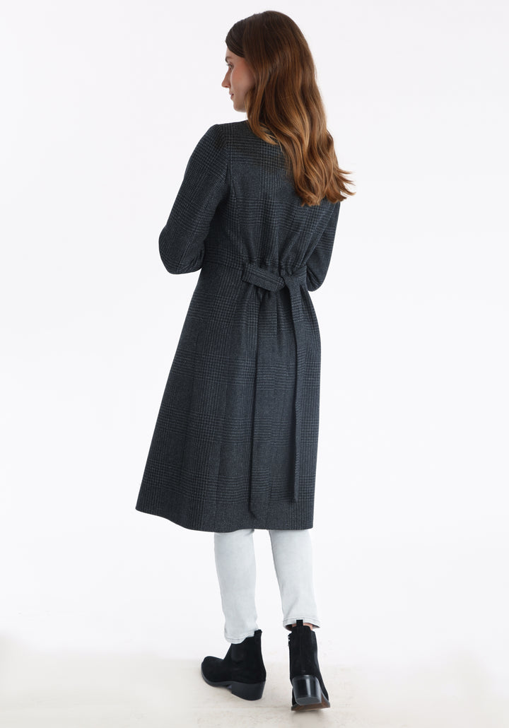 Model wearing the Hillsy coat in a black and charcoal grey Prince of Wales check, a wrap-style design with a standing collar, and tie belt, offering a softly tailored, elegant silhouette.