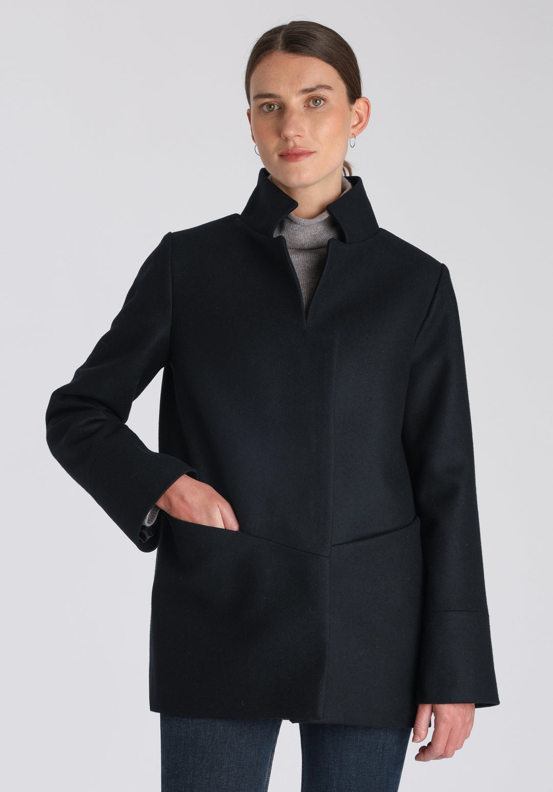 Model wearing the Jackson jacket in black cashmere blend, a structured, cocoon-shaped style with a cut-out standing collar, generous pockets, and deep panel detailing.
