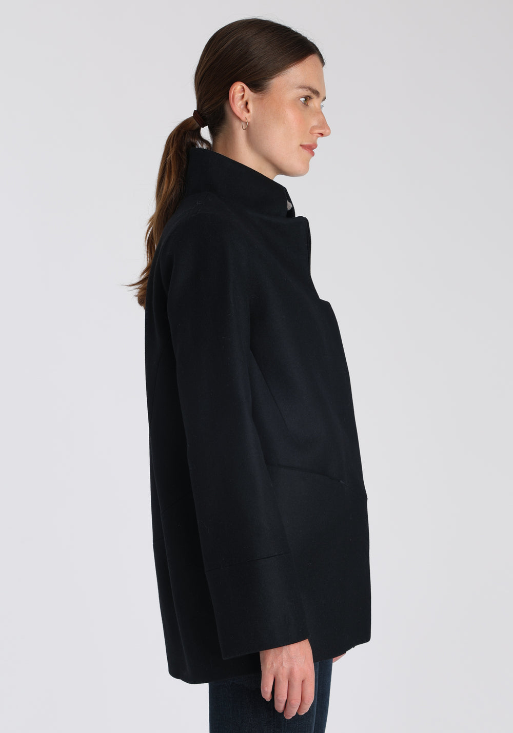 Model wearing the Jackson jacket in black cashmere blend, a structured, cocoon-shaped style with a cut-out standing collar, generous pockets, and deep panel detailing.