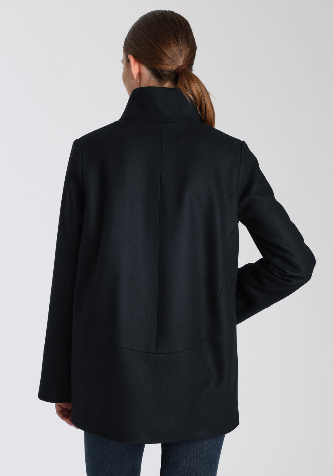 Model wearing the Jackson jacket in black cashmere blend, a structured, cocoon-shaped style with a cut-out standing collar, generous pockets, and deep panel detailing.
