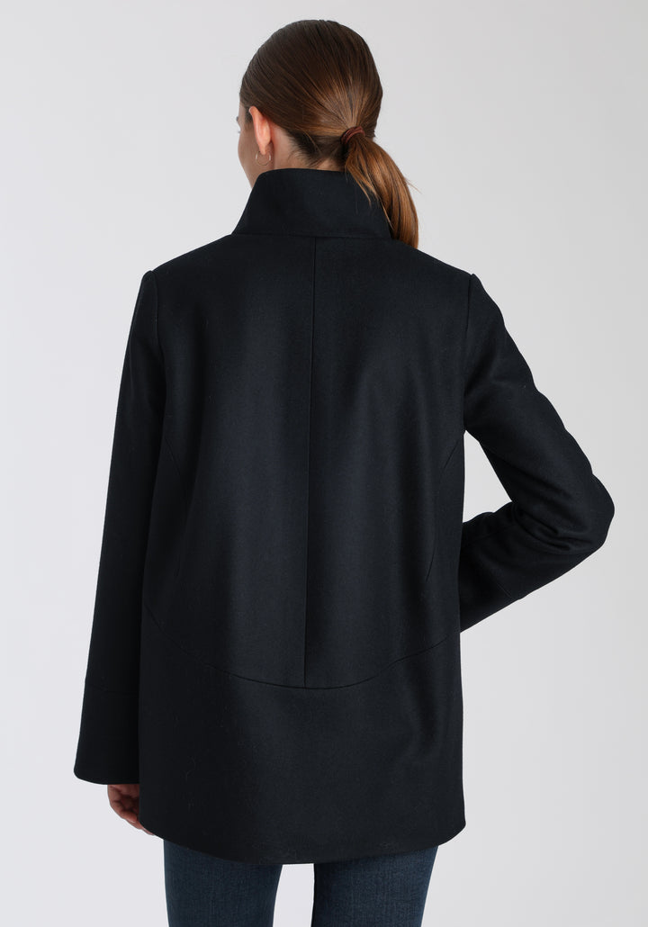 Model wearing the Jackson jacket in black cashmere blend, a structured, cocoon-shaped style with a cut-out standing collar, generous pockets, and deep panel detailing.
