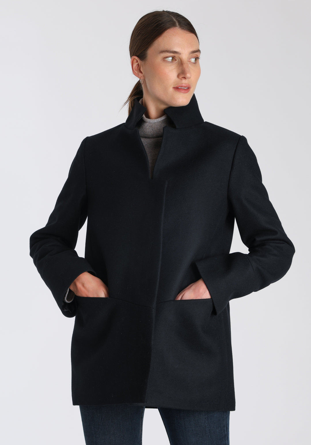 Model wearing the Jackson jacket in black cashmere blend, a structured, cocoon-shaped style with a cut-out standing collar, generous pockets, and deep panel detailing.