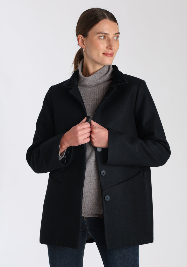 Model wearing the Jackson jacket in black cashmere blend, a structured, cocoon-shaped style with a cut-out standing collar, generous pockets, and deep panel detailing.