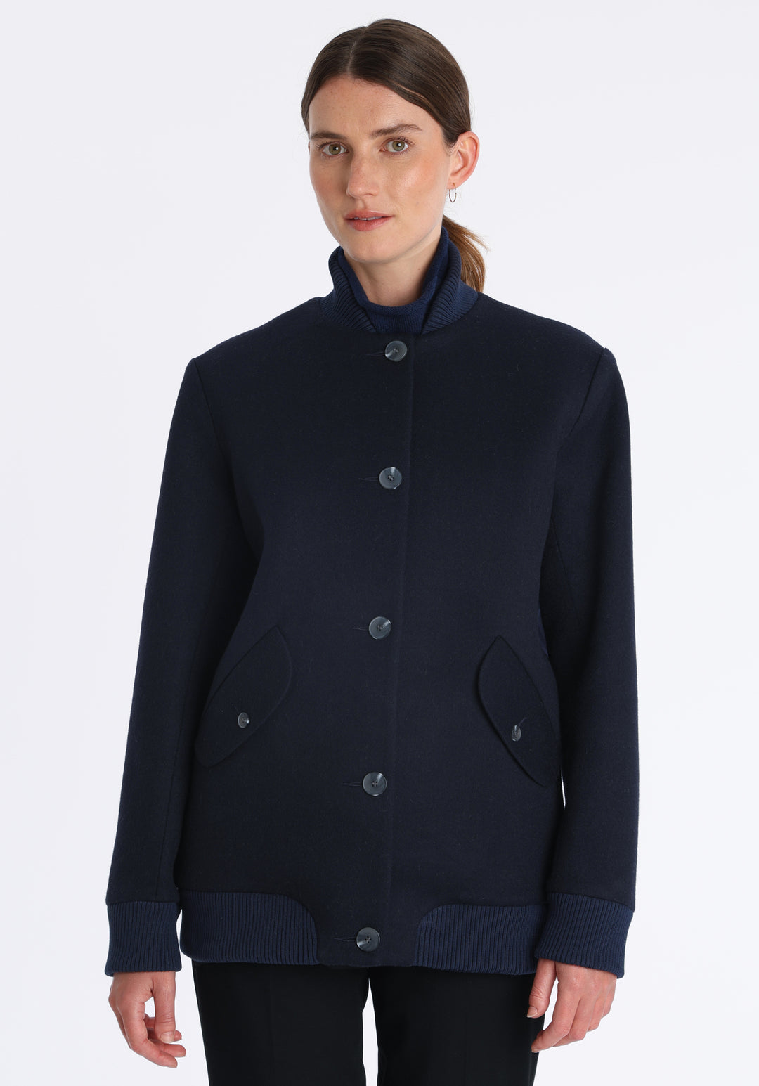 Model wearing the Jeffy jacket in navy merino wool, a baseball-inspired style with curved pocket flaps, front button fastenings, and ribbed knit trim, cut in a streamlined silhouette.