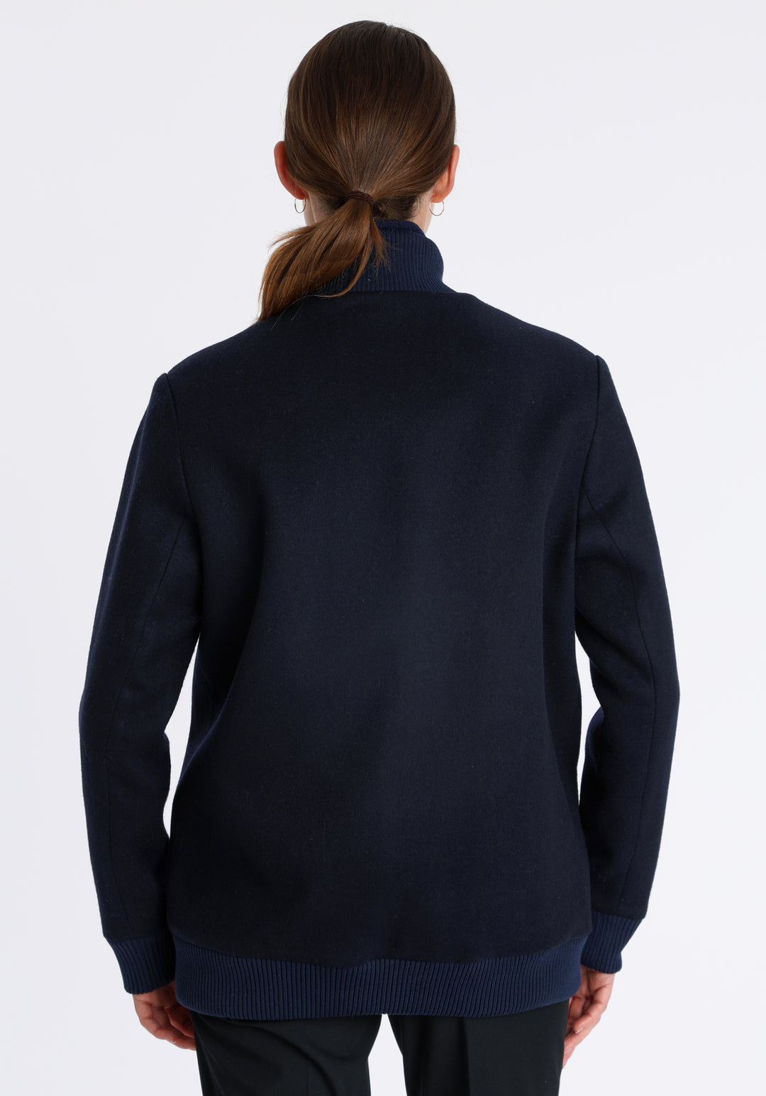 Model wearing the Jeffy jacket in navy merino wool, a baseball-inspired style with curved pocket flaps, front button fastenings, and ribbed knit trim, cut in a streamlined silhouette.