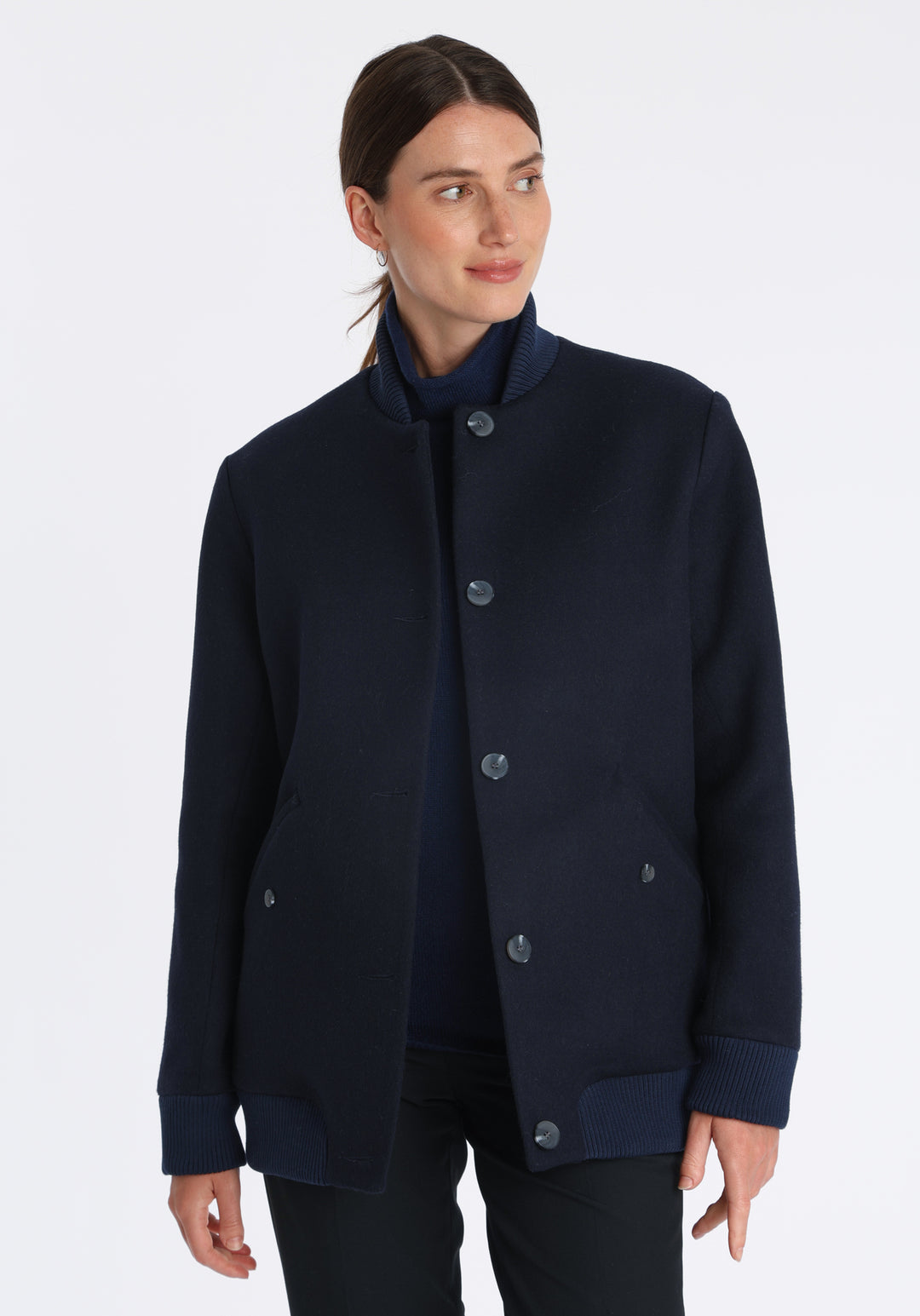 Model wearing the Jeffy jacket in navy merino wool, a baseball-inspired style with curved pocket flaps, front button fastenings, and ribbed knit trim, cut in a streamlined silhouette.