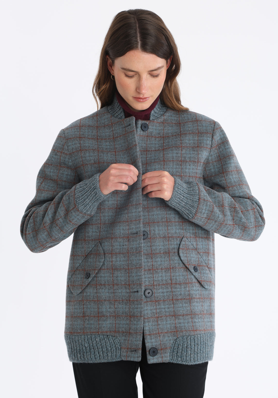 Model wearing the Jeffy jacket in silver blue and rust check merino wool, a baseball-inspired style with curved pocket flaps, front button fastenings, and ribbed knit trim, cut in a streamlined silhouette.