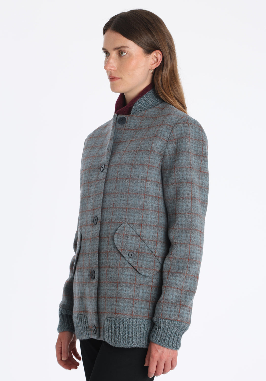 Model wearing the Jeffy jacket in silver blue and rust check merino wool, a baseball-inspired style with curved pocket flaps, front button fastenings, and ribbed knit trim, cut in a streamlined silhouette.