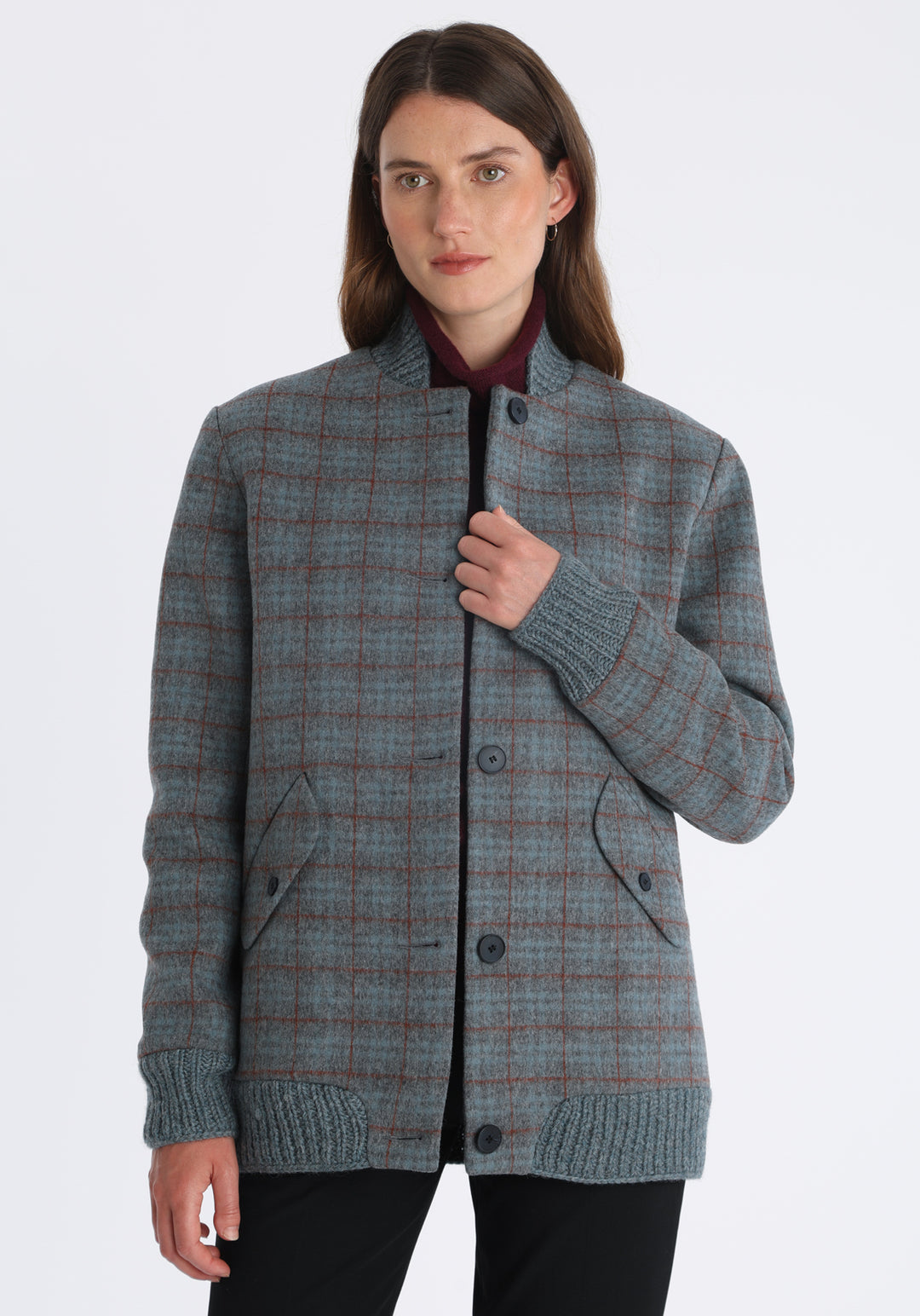 Model wearing the Jeffy jacket in silver blue and rust check merino wool, a baseball-inspired style with curved pocket flaps, front button fastenings, and ribbed knit trim, cut in a streamlined silhouette.