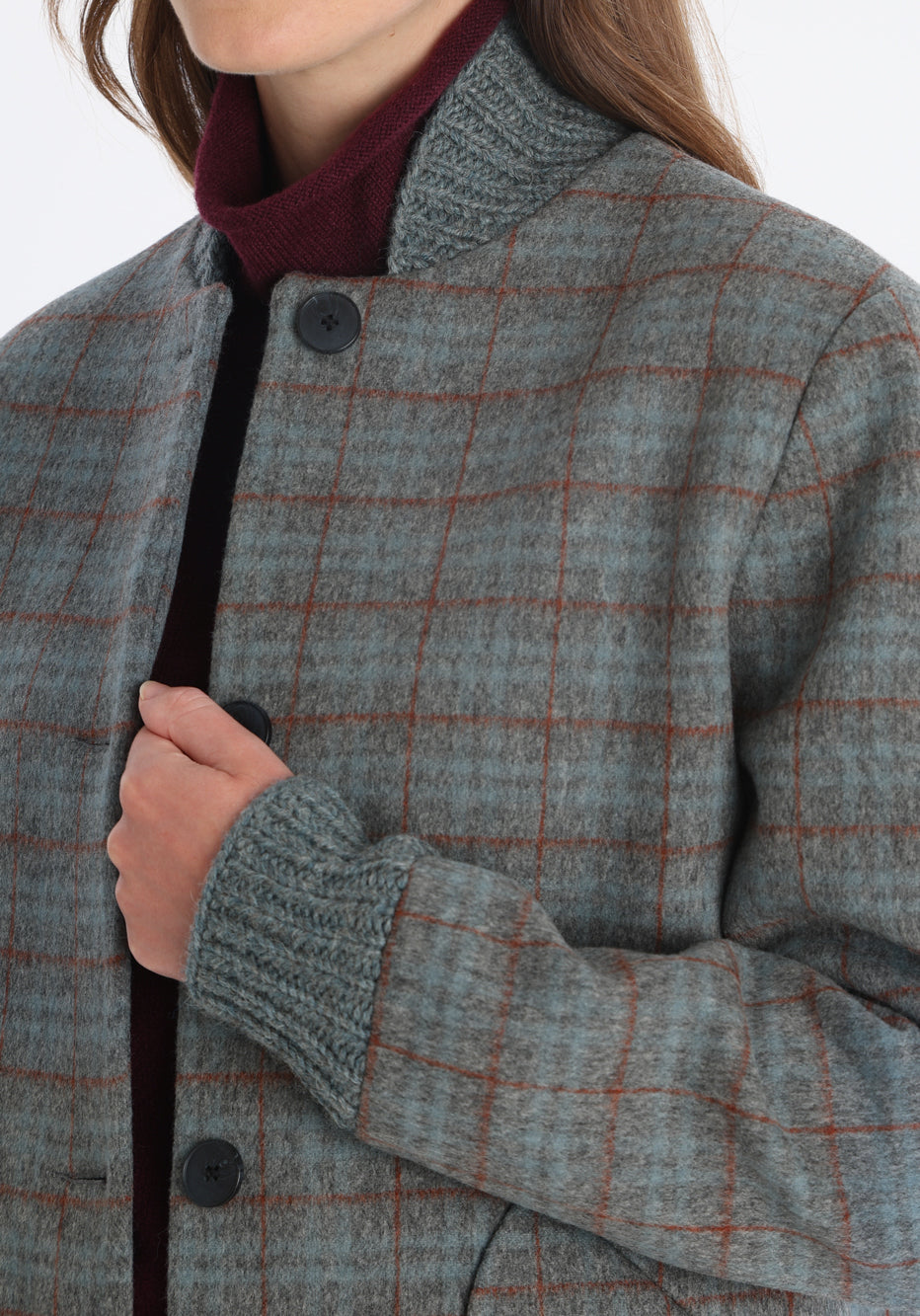 Model wearing the Jeffy jacket in silver blue and rust check merino wool, a baseball-inspired style with curved pocket flaps, front button fastenings, and ribbed knit trim, cut in a streamlined silhouette.