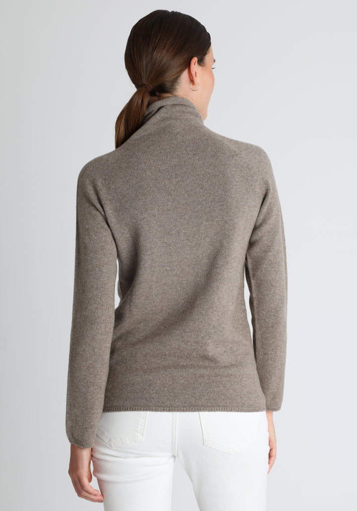 Model wearing the fine-knit cashmere jumper in mink, a slim fit style with a draped high neck, designed for layering and year-round wear.